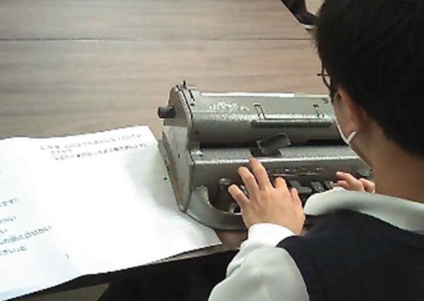 A student filling out a worksheet using a Braille typewriter